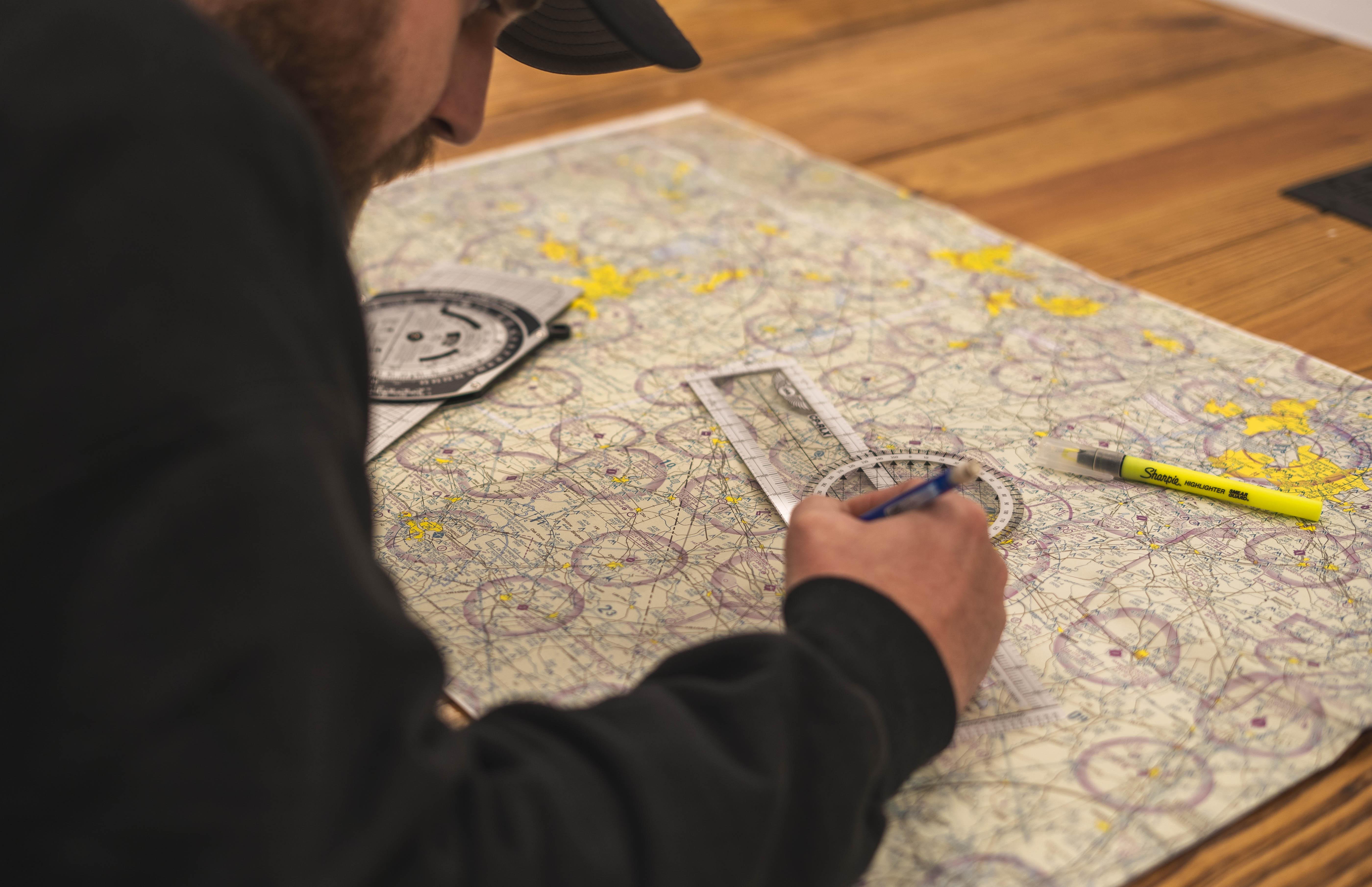 Student and instructor reviewing flight charts in a classroom setting.